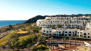 A coastal resort with white buildings, a golf course, and a view of the ocean.