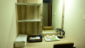 A bathroom with a wooden vanity, a towel, a tray with toiletries, and a mirror. - Hotel pams (Mayiladuthurai)