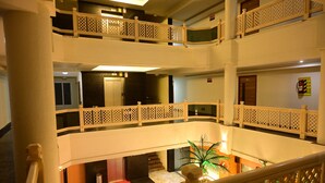 A multi-level hotel interior with a central atrium, balconies, and a staircase. - Hotel pams (Mayiladuthurai)
