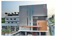 A modern building with a flat roof, large windows, and a prominent logo on the side. - Hotel pams (Mayiladuthurai)