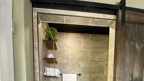Une salle de bain équipée de toilettes, d’un porte-serviettes et d’une étagère contenant des articles de toilette.