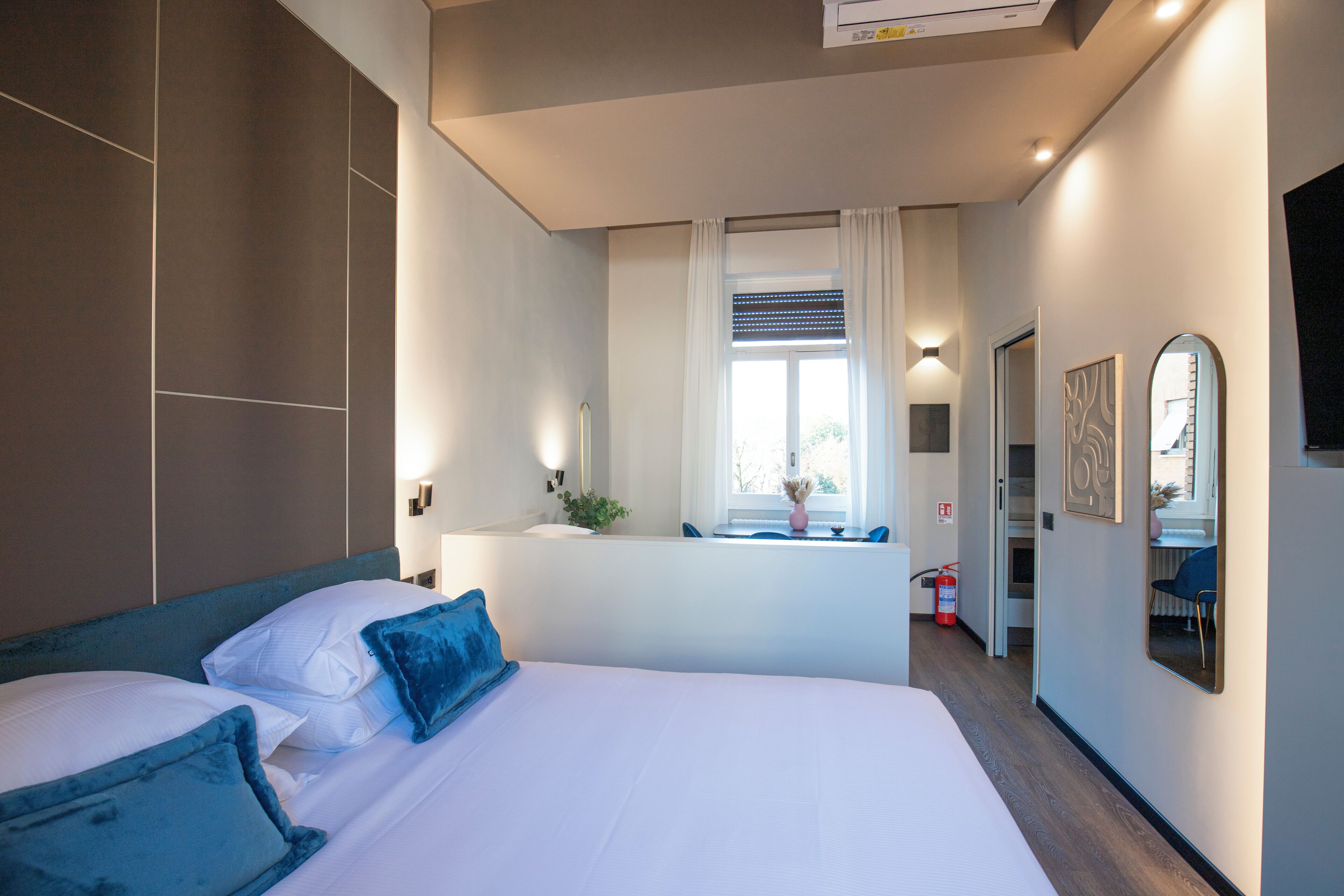 Habitació d'hotel moderna amb un llit gran, escriptori i finestra amb cortines.