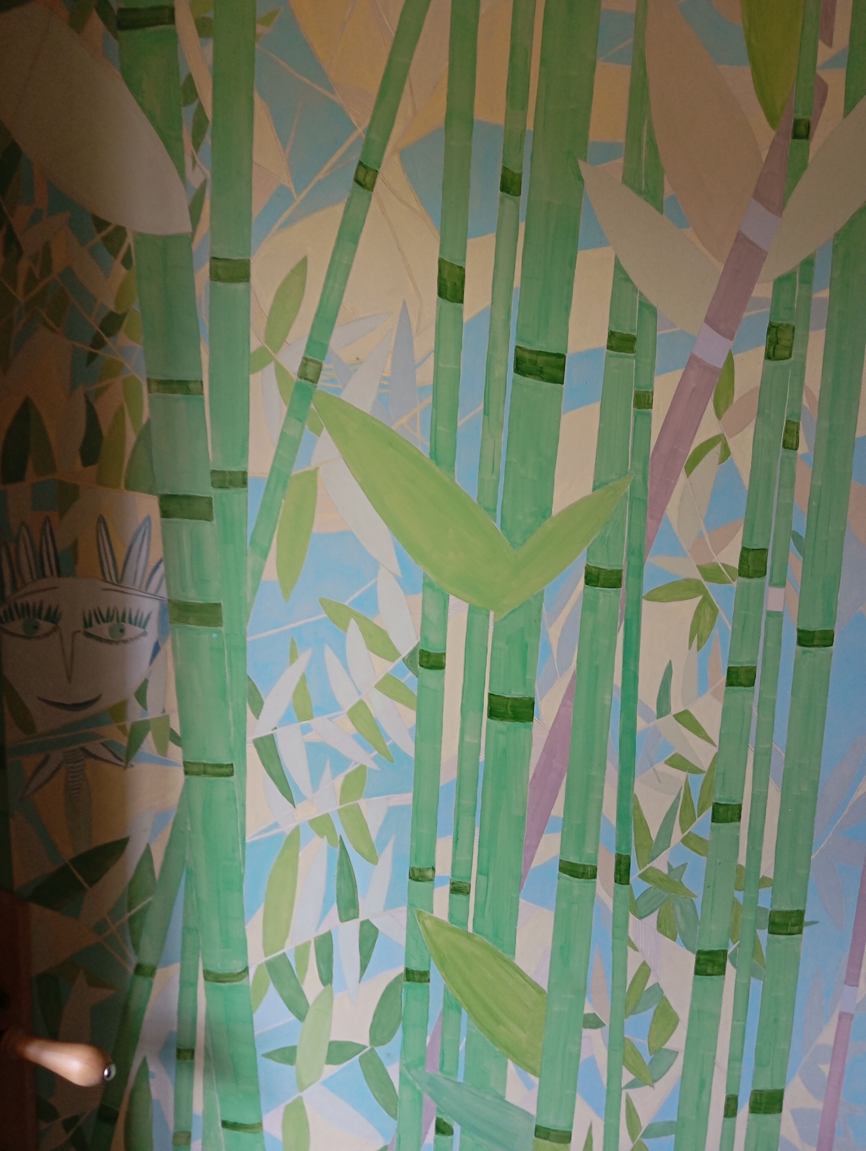 A room with a large window, a bed, and a wall with a bamboo pattern.