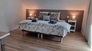 Une chambre à coucher comprenant un lit, des tables de chevet, une lucarne et une petite table de nuit.