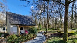 A house with a porch, a gravel path, and a forested area. - Chalet 7 - 8P-Pool -100m Black Frame (Saumur)
