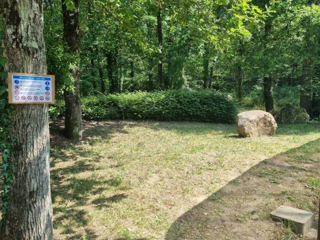 Une zone boisée avec une table de pique-nique et un panneau indiquant un espace réservé à la baignade.