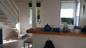 Una cocina con mostrador de madera, una tetera y un tarro. Se ve una escalera que conduce a otra habitación.