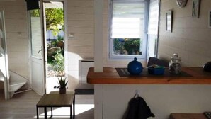 Cocina pequeña con ventana, una mesa y una chaqueta colgada.