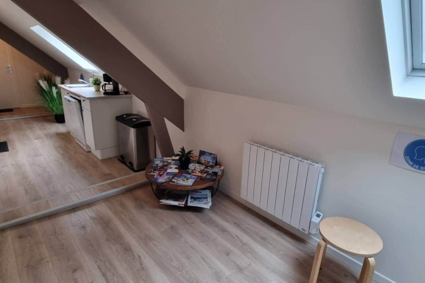 Eine moderne Küche mit Einbauofen, kleinem Mülleimer und Essbereich mit Tisch und Stühlen.