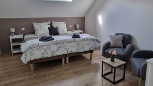 Ein Schlafzimmer mit Bett, Nachttischen, einem Sessel, einem kleinen Tisch und einem Oberlicht.