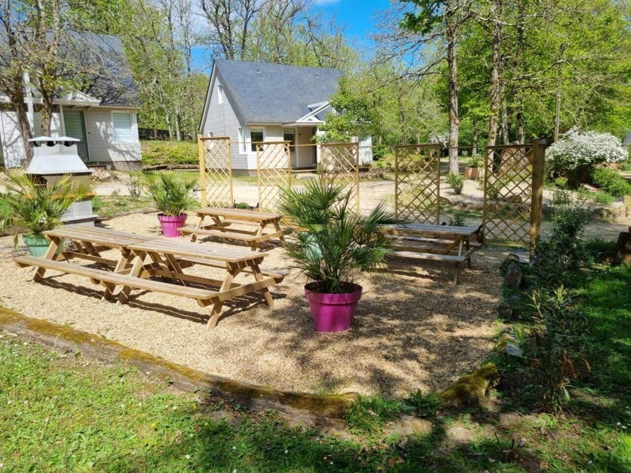 Ein Gartenbereich mit Picknicktischen und Blumentöpfen.