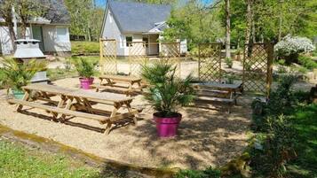 Ein Gartenbereich mit Picknicktischen und Blumentöpfen.