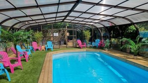 Ein überdachter Pool mit bunten Stühlen und Topfpflanzen.