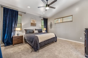 A bedroom with a bed, nightstands, a ceiling fan, and a dresser.