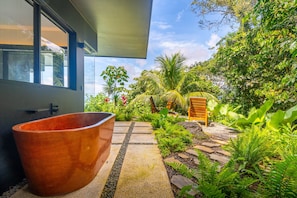 A modern outdoor space with a large terracotta planter, a wooden bench, and a variety of tropical plants. - Jungle Luxury Villa • 3BR w/ Pool & Ocean View (Savegre)