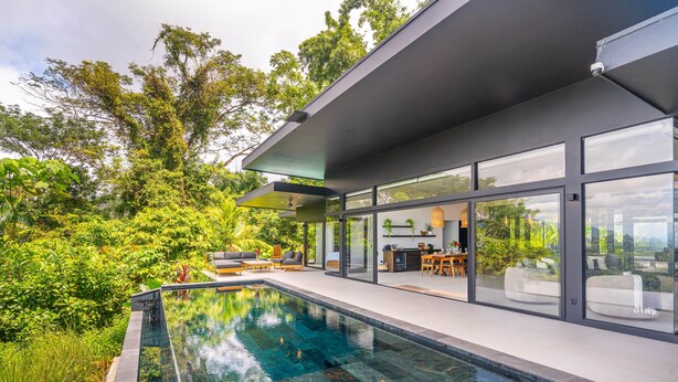 A modern house with a swimming pool, large glass windows, and a lush garden. - Jungle Luxury Villa • 3BR w/ Pool & Ocean View (Savegre)