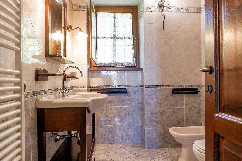 A bathroom with a sink, mirror, window, and toilet.