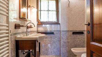 A bathroom with a sink, mirror, window, and toilet.