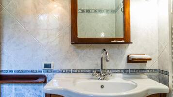 Un baño con lavamanos, espejo y toallero.