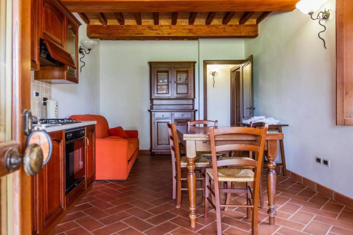 Une cuisine de taille réduite avec des meubles en bois, une table à manger avec des chaises et un canapé rouge.