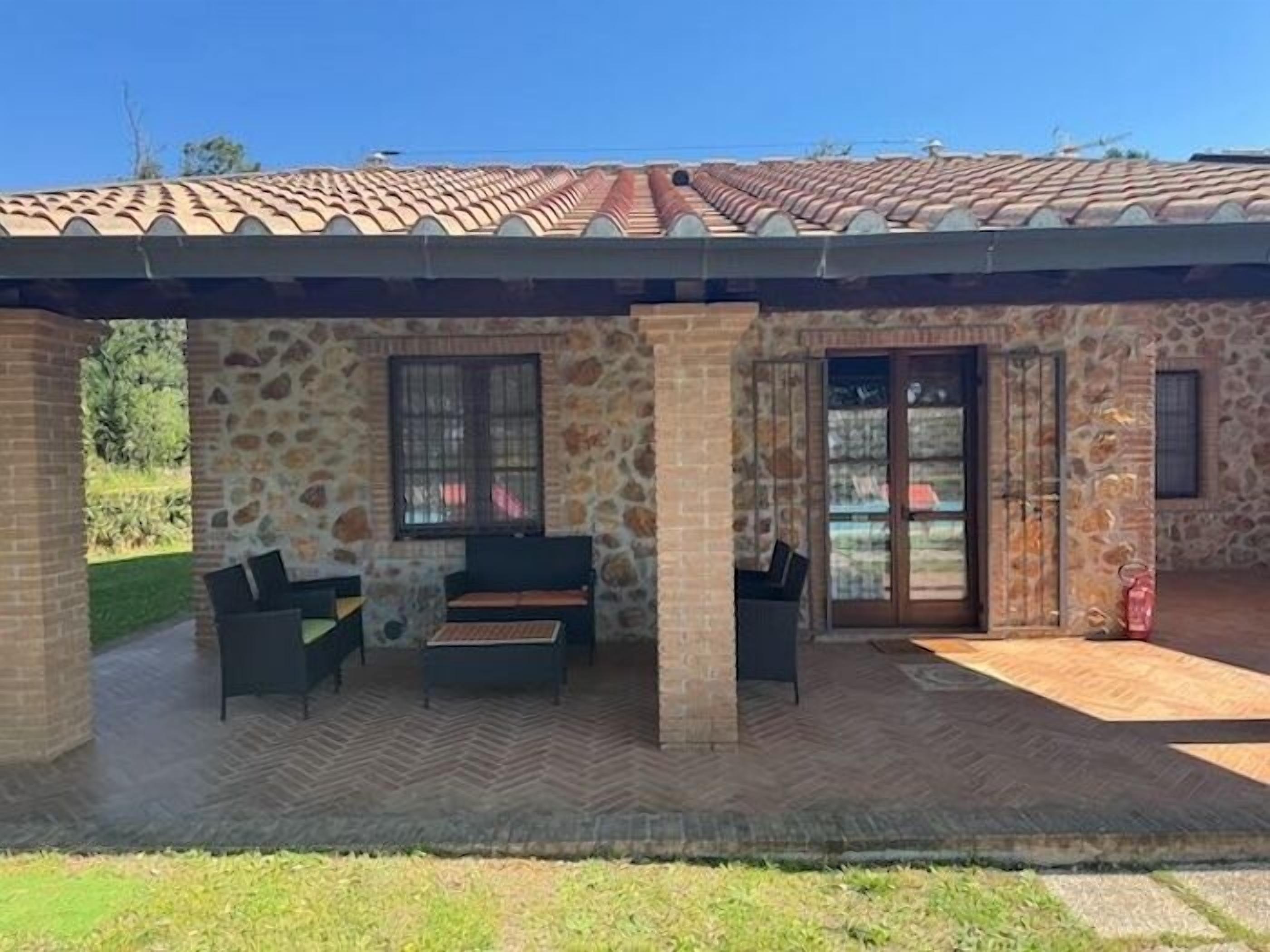 A covered outdoor seating area with stone walls and a tiled roof.