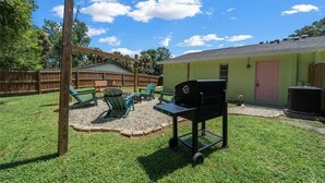 A backyard with a grill, green lawn, wooden fence, and a small shed. - Pet-Friendly Crystal River Retreat - Near Manatees & Golf (Crystal River)