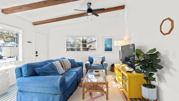 A living room with a blue sofa, a yellow cabinet, and a ceiling fan. - Pet-Friendly Crystal River Retreat - Near Manatees & Golf (Crystal River)