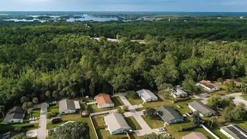 Vista aérea de una zona residencial con varias casas, carreteras y una gran masa de agua al fondo.