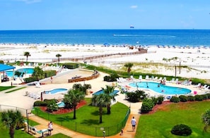 A resort with multiple swimming pools, a beach, and a view of the ocean.