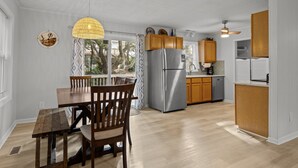 Eine moderne Küche mit Edelstahlkühlschrank, Holzschränken und einem Essbereich mit Holztisch und Stühlen.