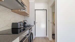 A modern kitchen with a built-in oven, microwave, and coffee maker. - The York | Light + Spacious CBD Apartment (Cape Town)