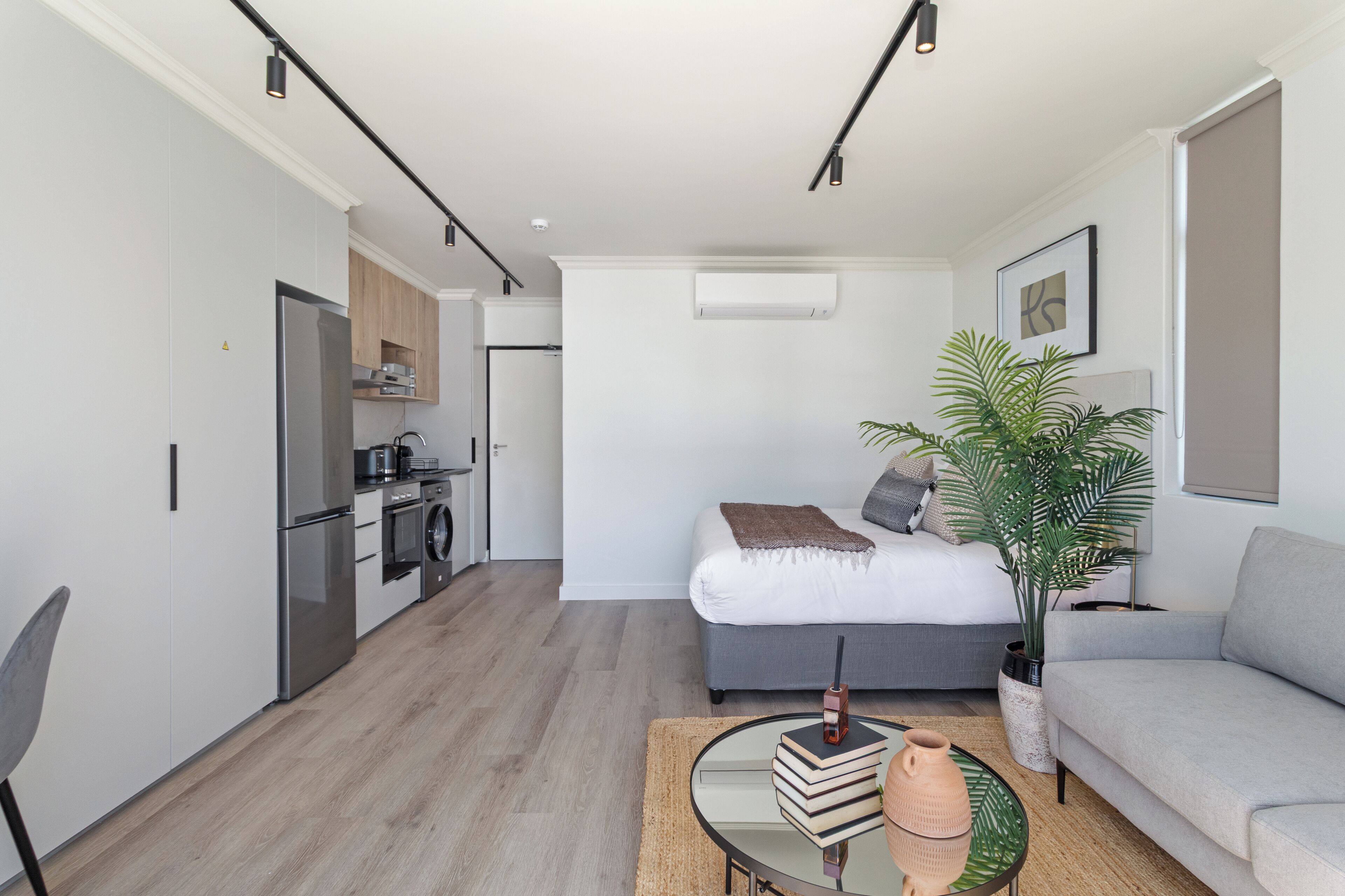 A modern apartment with a kitchenette, a bed, a sofa, and a dining area.