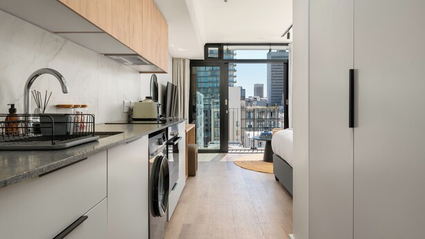 A modern kitchen with a built-in oven, a sink, and a window overlooking a cityscape. - Stylish Apartment at The York | Gym (Cape Town)
