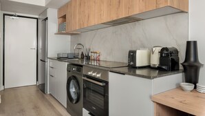 A modern kitchen with stainless steel appliances, wooden cabinets, and a marble backsplash. - Stylish Apartment at The York | Gym (Cape Town)