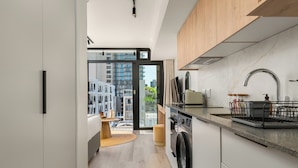 Una cocina moderna con lavadora y secadora integradas, armarios de madera y un amplio ventanal con vistas a la ciudad.