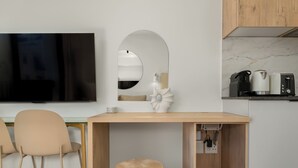 Una cocina moderna con una mesa de madera, dos sillas, un espejo redondo y un televisor montado en la pared.
