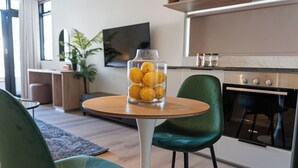 Een moderne keuken met een ronde houten tafel, groene stoelen en een glazen pot met citroenen op tafel.