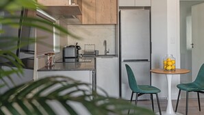 Een moderne keuken met een roestvrijstalen koelkast, houten keukenkastjes en een kleine eettafel met twee stoelen.