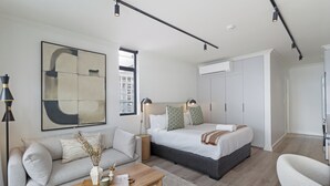 Un dormitorio moderno con una cama grande, un sofá, una mesita de centro y un cuadro en la pared.