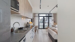 Una cocina moderna con un microondas Bosch, un lavabo y una estufa, un comedor con mesa y sillas, y un dormitorio con cama y vistas a la ciudad a través de amplios ventanales.