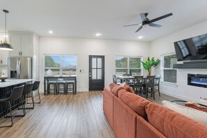 A modern kitchen with a dining area, a sofa, and a TV.
