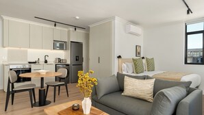 A modern apartment with a kitchen, dining area, and living room. It includes a sofa, a coffee table, and a vase with flowers. - The York | Spacious CBD Apartment (Cape Town)
