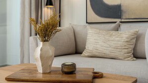 A wooden table with a vase of dried plants and a small container.