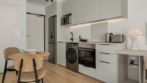 A modern kitchen with built-in appliances, a dining area with chairs, and a lamp.