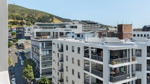 A modern multi-story building with balconies, large windows, and a flat roof.