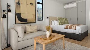 A modern bedroom with a bed, a sofa, a wooden table, and a large abstract painting.