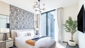 Ein modernes Schlafzimmer mit einem großen Bett, einem Nachttisch, einer Topfpflanze und Blick auf die Stadt.