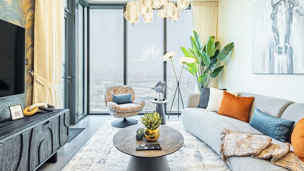 Ein modernes Wohnzimmer mit Sofa, Sessel, Couchtisch und einem großen Fenster mit Blick auf die Stadt.