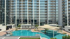Ein modernes Hochhaus mit einem Dachpool und Liegestühlen.