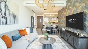Ein modernes Wohnzimmer mit grauem Sofa, Couchtisch und Fernseher auf einem schwarzen Lowboard.
